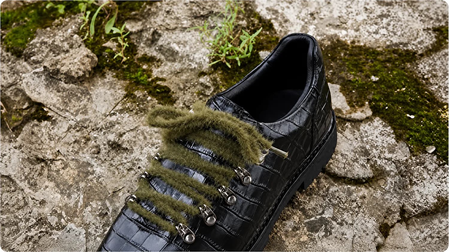 Black croc leather sneaker on mossy rock
